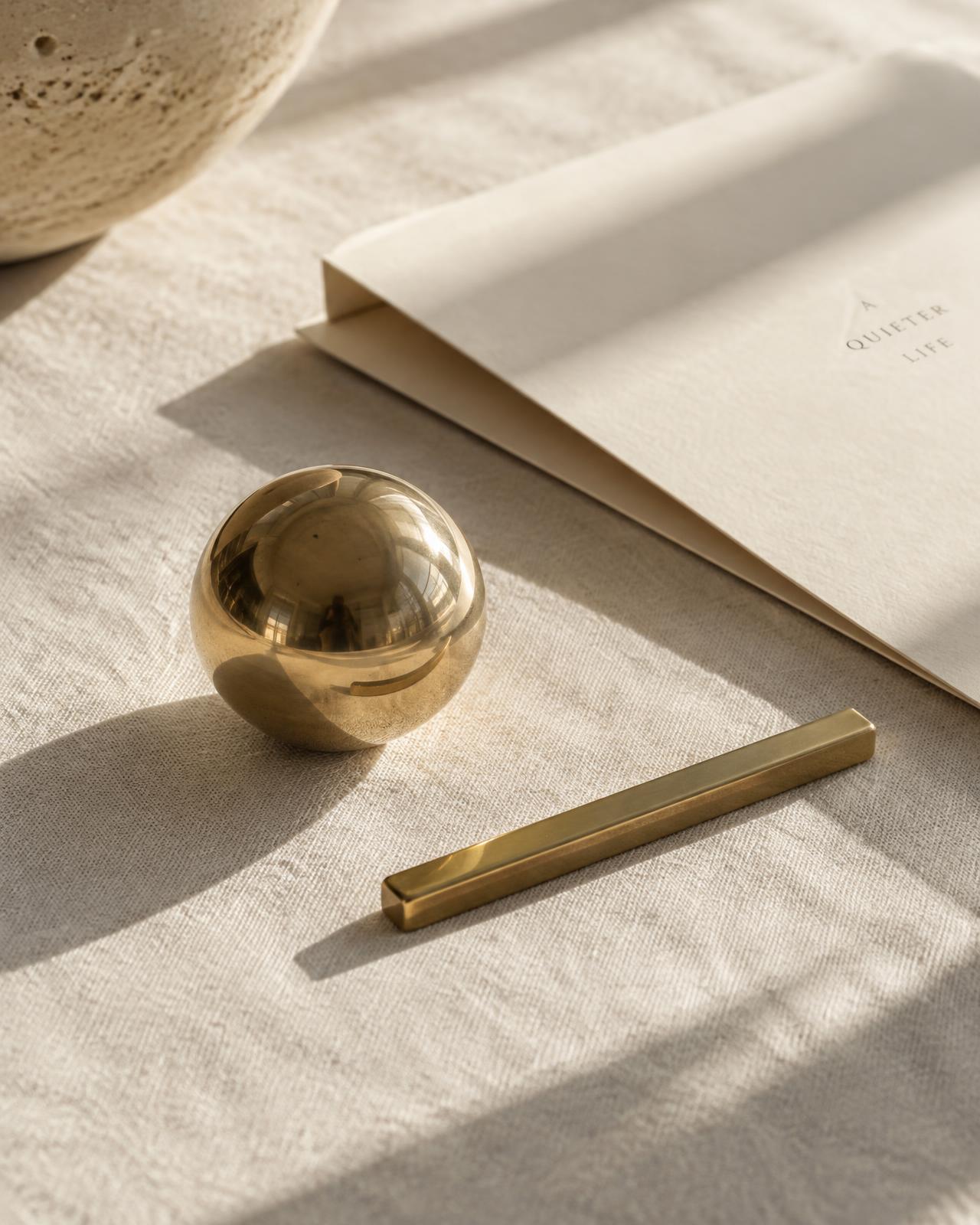 Brass sphere and gold bar on ivory linen